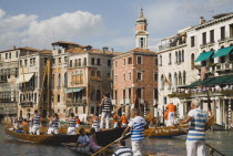 Italy, Veneto, Venice, Grand Canal, Participants in the Regata Storico historical Regatta held annually in September approaching the Rialto bridge with onlookers gathered on the balconies of canalside...