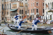 Italy, Veneto, Venice, Grand Canal, Participants in the Regata Storico historical Regatta held annually in September in blur of movement as they approach the Rialto bridge with onlookers on the balcon...