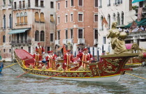 Italy, Veneto, Venice, Grand Canal, Participants in the Regata Storico historical regatta held annually in September wearing traditional costume and rowing red and gold painted gondola approaching the...