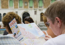 Italy, Veneto, Venice, Grand Canal, Female tourist reading map guide of Venice during Regatta Storico historical annual regatta.