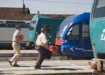 Italy, Veneto, Venice, Commuters running to board local train with regional trains on platforms at side.