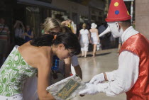 Italy, Veneto, Verona, Street performer dressed in clown costume with young women signing petition.