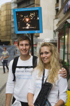 Hungary, Pest County, Budapest, attractive young student couple promoting mobile internet access near Saint Stephens Basilica.