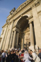 Hungary, Pest County, Budapest, bride and groom greeting wedding guests on steps of Saint Stephens Basilica after service.