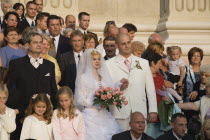 Hungary, Pest County, Budapest, bride and groom with wedding guests pose for photographs on steps of Saint Stephens Basilica after service.