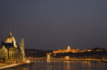 Hungary, Budapest, View along the River Danube at night with the Parliament building on the left, the Chain Bridge and the Royal Palace on the right all illuminated brightly.