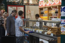 Hungary, Pest County, Budapest, queue of customers at stall selling snacks, salads and other dishes at Nagy Vasarcsarnok, the Central Market.