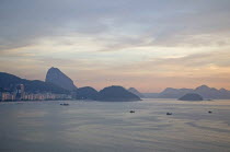 BRAZIL Rio de Janeiro Copacabana and Sugarloaf Mountain at dawn with fishing boats in the bay dreamy sky and sea.