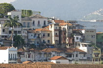 BRAZIL Rio de Janeiro Saude downmarket neighbourhood traditional clay tile roofs and washing hung out of windows palm trees and favela or slum on the hillside.