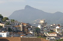 BRAZIL Rio de Janeiro Rooftops of Saude neighbourhood with a hillside favela or slum and the statue of Christ the Redeemer atop Corcovada mountain traditional tile roofs and palm trees.
