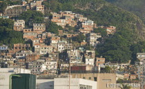 BRAZIL Rio de Janeiro Favela or slum on hillside above Copacabana neighbourhood, greenery and COPACABANA in large letters on building in foreground.