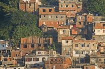 BRAZIL Rio de Janeiro Favela or slum on hillside above Copacabana neighbourhood, red brick houses greenery and TV dish antenna.