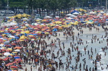 BRAZIL Rio de Janeiro Copacabana beach, crowds on the beach and in the sea, bikinis multi-coloured beach umbrellas.
