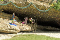 BRAZIL Rio de Janeiro Grotto in rocks in Arpoador Park off Ipanema beach, statue of Jesus Christ gold stars flowers and a wire candle holder.