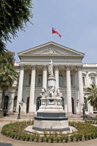 Chile, Santiago, Camara de Diputados, Chamber of Deputies with Chilean flag flying on the building and ornamental religious statue in the foreground.