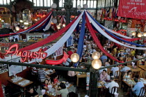 Chile, Santiago, Seafood restaurant section of Central Market with diners at tables eating under red white and blue hanging decorations