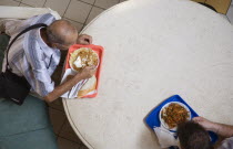 Hungary, Pest County, Budapest, looking down on two men having lunchtime meal seated at circular table in Nagy Vasarcsarnok the Central Market.