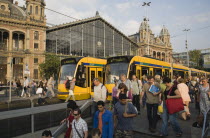 Hungary, Pest County, Budapest, trams and crowd of passengers in front of rail terminus Budapest Nyugati palyaudvar and walking down steps to metro in foreground with one man turning to look at anothe...