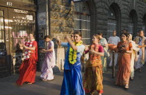 Hungary, Pest County, Budapest, Hare Krishna devotees singing and dancing on Andrassy UtIn Pest with graffiti covered doorway behind. The International Society for Krishna Consciousness or ISKCON, als...