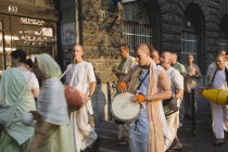 Hungary, Pest County, Budapest, Hare Krishna devotees singing and dancing on Andrassy UtIn Pest, with graffiti covered doorway behind. The International Society for Krishna Consciousness or ISKCON, al...