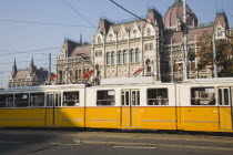 Hungary, Pest County, Budapest, yellow tram passing the Parliament Building.