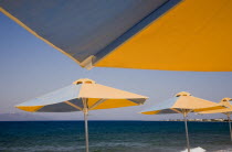 Greece, Dodecanese, Kos, blue and yellow striped parasols on beach outside Kos Town.