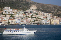 Greece, Northern Aegean, Samos, Vathy, ferry between Samos and Kusadasi in Turkey as it leaves Vathy. Town houses spread across hillside behind.