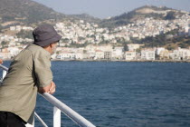 Greece, Northern Aegean, Samos, Vathy, Tourist rests on handrail on deck of ferry between Samos and Kusadasi in Turkey as it leaves Vathy, Samos.