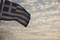 Greece, Northern Aegean, Samos, Vathy, Greek flag flying from ferry between Samos and Kusadasi in Turkey as it leaves Vathy, Samos with silvery cloud in evening sky behind. 