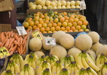 Greece, Attica, Athens, Central Market, Fruit and vegetable summer produce for sale on grocers stall including melons, bananas and carrots.