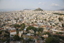 Greece, Attica, Athens, Mount Lycabettus rising in central Athens with densely populated city below part framed by wall in foreground.