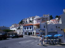 Portugal, Algarve, Carvoeiro, Typical street with white washed buildings, tourists and traffic.