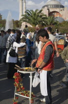 Turkey, Istanbul, Sultanahmet, Man standing at food stall in front of Hagia Sophia with crowds of people behind.