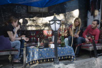 Turkey, Istanbul, Sultanahmet, Young couple at shaded cafe with a hookah or Nargile water pipe, others sitting opposite drinking from tea glasses. 