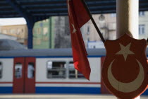 Turkey, Istanbul, Sultanahmet, Istanbul Sirkeci Terminal, Turkish flag and emblem in foreground with train on platform behind. Sirkeci GarA is a terminus main station of the Turkish State Railways or...