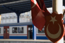 Turkey, Istanbul, Sultanahmet, Istanbul Sirkeci Terminal, Turkish flag and emblem in foreground with train at platform behind. Sirkeci is a terminus main station of the Turkish State Railways or TCDD...