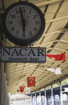Turkey, Istanbul Sultanahmet, Station clock giving time of three minutes to six on platform with Turkish flags hanging from roof over platform behind. Istanbul Sirkeci Terminal or Sirkeci is a terminu...