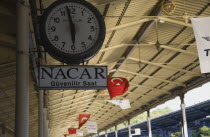 Turkey, Istanbul, Sultanahmet, Station clock on platform giving time of three minutes to six with Turkish flags hanging from roof over platform beyond. Istanbul Sirkeci Terminal or Sirkeci GarA is a...