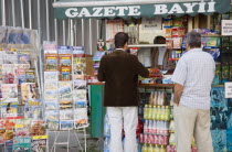 Turkey, Istanbul, Sultanahmet, Customers at newspaper kiosk with magazine stand and display of maps, postcards, snacks and soft drinks.