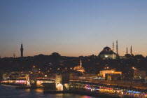 Turkey, Istanbul, Sultanahmet, The Golden Horn. The New Mosque or Yeni Camii at left, the Galata Bridge and Suleymaniye Mosque at right illuminated at dusk.