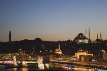 Turkey, Istanbul, Sultanahmet, The Golden Horn. The New Mosque or Yeni Camii at left, the Galata Bridge and Suleymaniye Mosque at right illuminated at dusk.