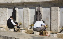 Turkey, Istanbul, Sultanahmet, The New Mosque or Yeni Camii. Two men washing and making ablutions before prayer.