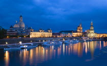 GERMANY, Saxony, Dresden, The city skyline at night with cruise boats moored on the River Elbe in front of the illuminated embankment buildings on the Bruhl Terrace of the Art Academy the Frauenkirche...