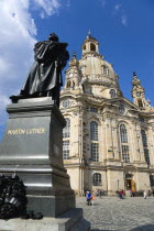 GERMANY, Saxony, Dresden, The restored Baroque church of Frauenkirch in Neumarkt with a statue of Martin Luther in the foreground and tourists walking in the square.