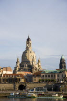 GERMANY, Saxony, Dresden, Cruise boat moored on the River Elbe in the late afternoon light in front of the embankment buildings on the Bruhl Terrace busy with tourists in front of the Frauenkirche Chu...