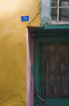 Turkey, Aydin Province, Kusadasi, Detail of exterior facade of house in the old town numbered 1A.  With yellow and pink painted walls and turquoise painted door and window frames.