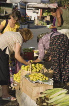 Turkey, Aydin Province, Kusadasi, Woman from local farm selling fruit and vegetables to shoppers at fresh produce market in town.