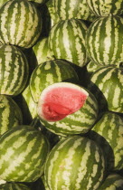 Turkey, Aydin Province, Kusadasi, Fresh watermelon on sale at town produce market with fruit at centre cut open to reveal red flesh and seeds.