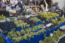 Turkey, Aydin Province, Kusadasi, Stall with display of grapes, figs, beans and chilies for sale in busy market.