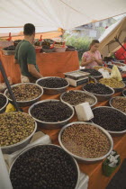 Turkey, Aydin Province, Kusadasi, Stall at weekly market  selling olives and nuts with male stallholderand young girl standing behind display and set of electronic scales.